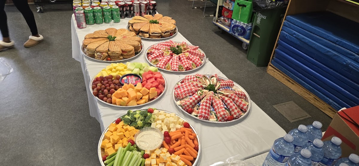 A full catering spread from Chuck's Deli with panini platters, fruit platters, vegetable platters, and sandwich trays on a long table