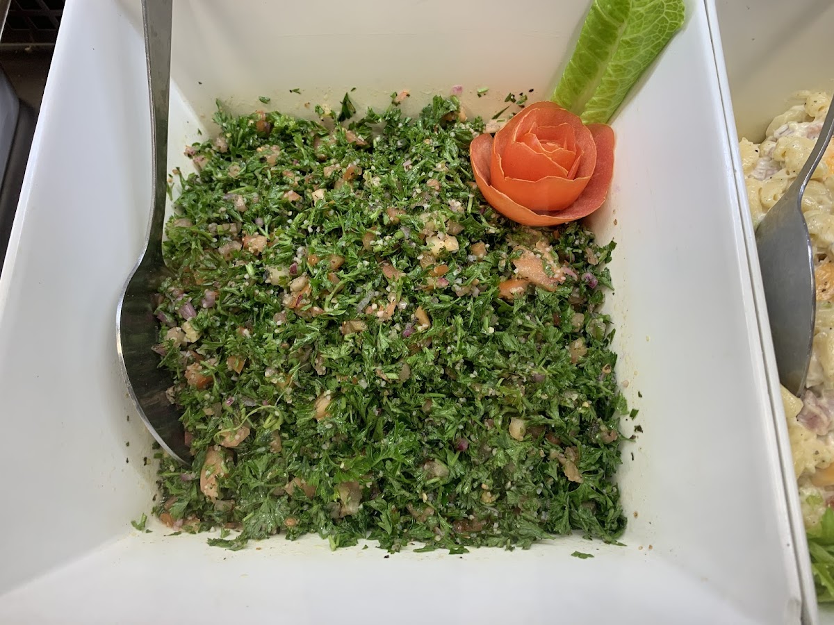 Fresh tabbouleh salad garnished with a decorative tomato rose, showing the homemade quality of Chuck's sides