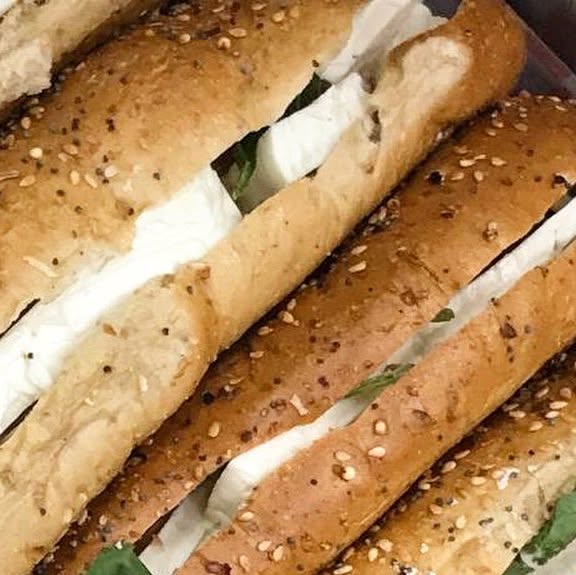 Fresh paninis with mozzarella and basil lined up in the deli case