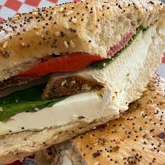 Close-up of a Chuck's Deli panini with fresh mozzarella, tomato, basil, and salami on seeded bread