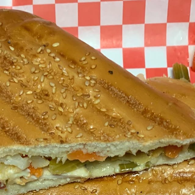 Close-up of a golden grilled panini with sesame seeds showing the cross-section of fillings