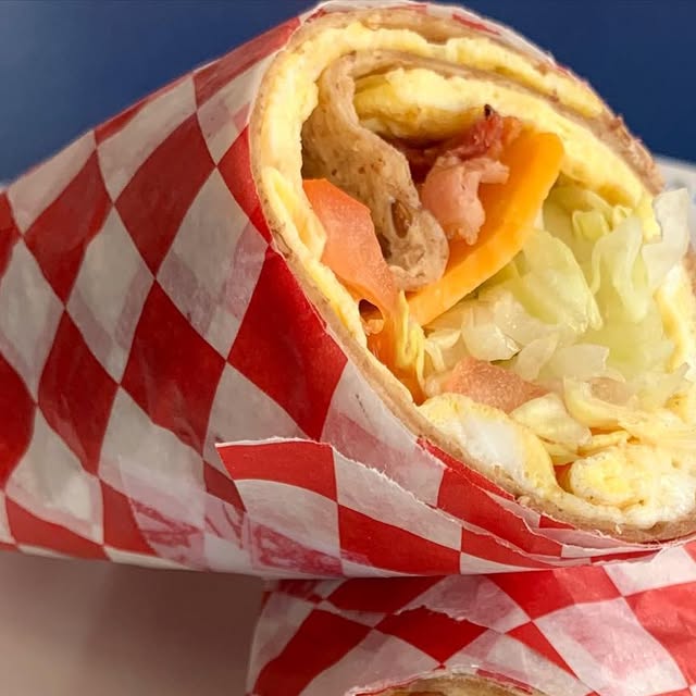 Fresh wrap with egg, cheese, and vegetables in checkered deli paper